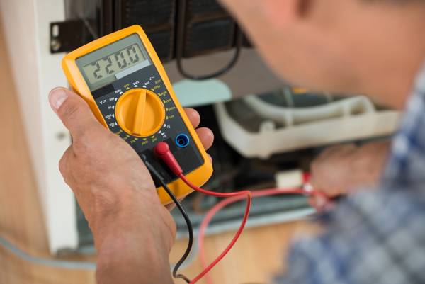 HVAC repairman checking his guage that reads 220