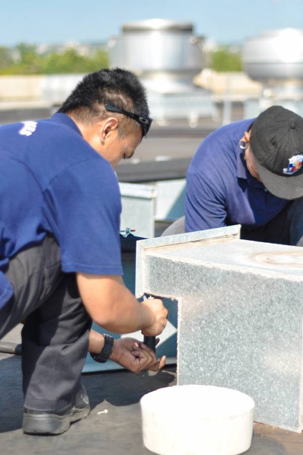 two HVAC technicians on the roof repairing industrial refrigeration equipment